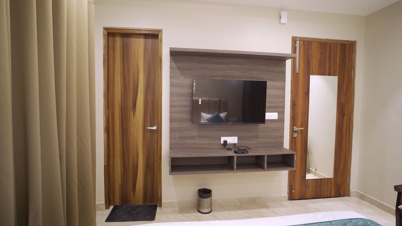 Quarto com guarda-roupa de madeira, televisão integrada e espelho.