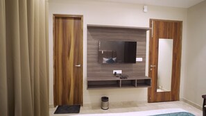 A room with a wooden wardrobe, a built-in TV, and a mirror.