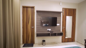 Quarto com guarda-roupa de madeira, televisão integrada e espelho.