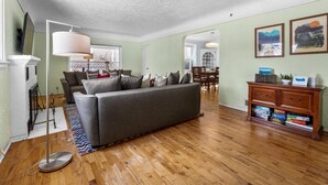 A living room with a sofa, a coffee table, a lamp, a fireplace, and a bookshelf. - DOG FRIENDLY & EPIC Location! Walk 2 Blocks to Hyde Park | Cozy Up by the Fireplace! (Boise)