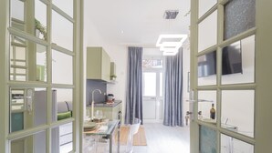 Una cocina moderna con zona de comedor, un ventanal con cortinas y una puerta visible.