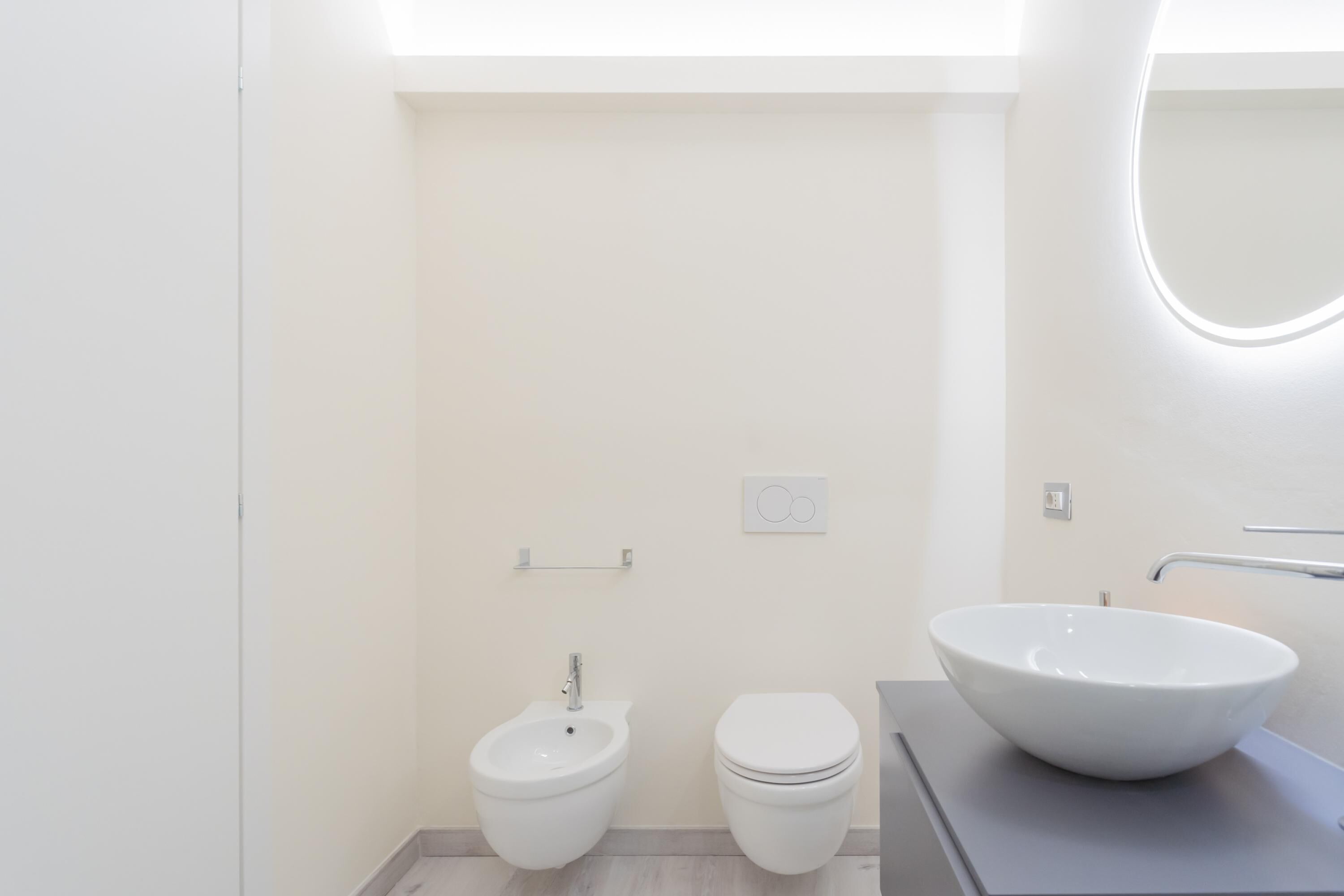 A modern bathroom with a bidet, toilet, and a large vessel sink.