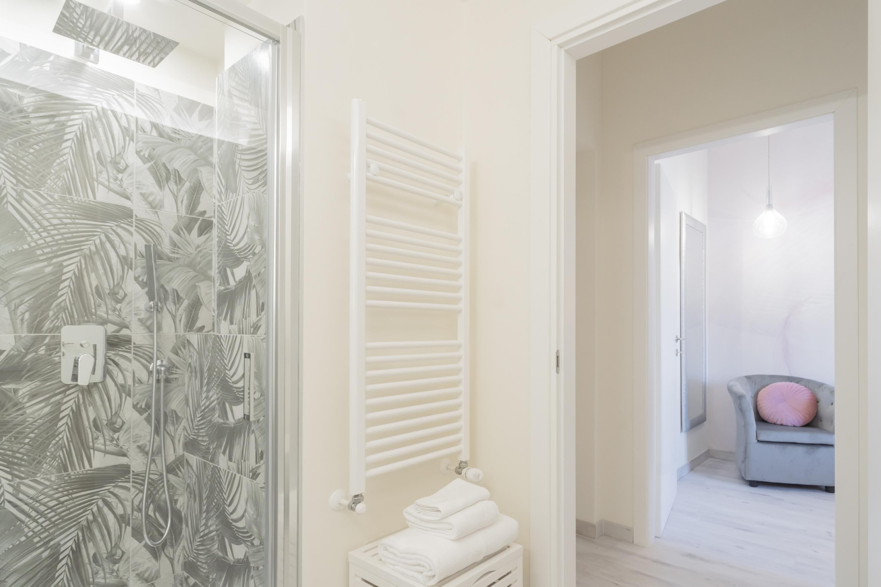 Une salle de bain avec une douche à parois de verre, un porte-serviettes blanc et un bac de rangement blanc.