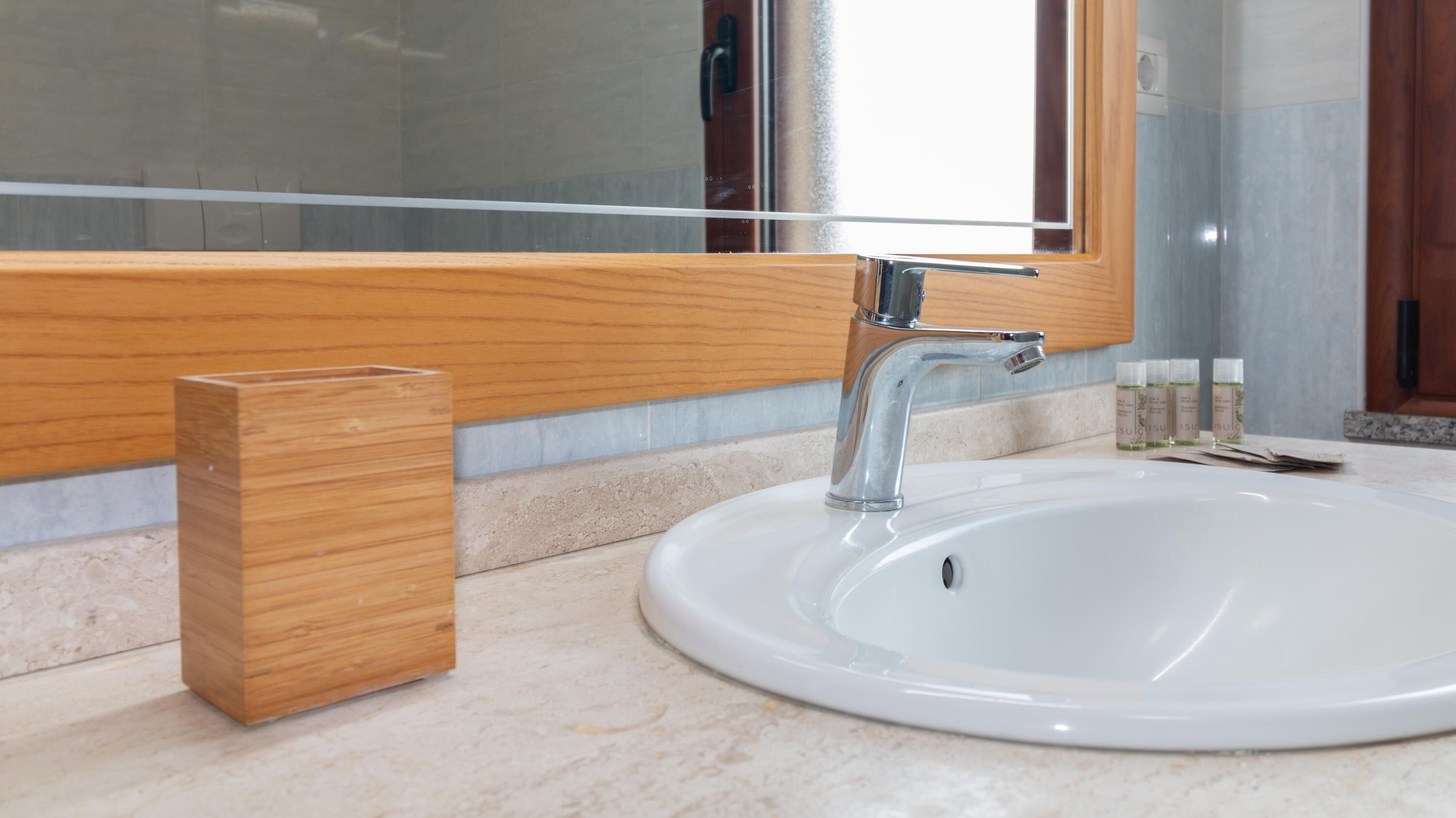 Une salle de bain avec un lavabo blanc, un porte-savon en bois et un miroir au-dessus du lavabo.