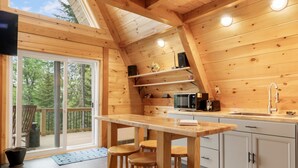 Un interior de madera con una zona de cocina que incluye una barra, taburetes y un microondas.