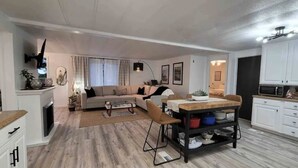 A modern living room with a sofa, coffee table, and dining area with a wooden table and chairs.