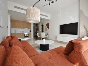 Relax in this stylish living room with a plush sofa, flat-screen TV, and modern kitchen area.