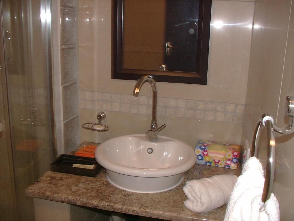 A bathroom with a sink, mirror, towel rack, and a shower area.
