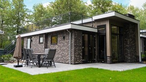 Et moderne hus med terrasse, udendørs møbler og en glasdør.