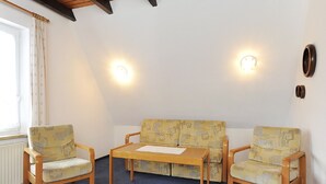 Une pièce comprenant un canapé, deux fauteuils, une petite table et un radiateur.