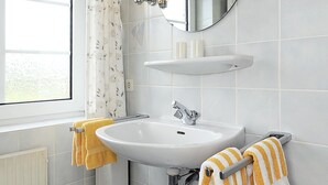 Une salle de bain équipée d’un lavabo, d’un miroir et d’un porte-serviettes.