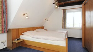 Une chambre à coucher avec un lit en bois, une table de chevet et une fenêtre avec des rideaux.
