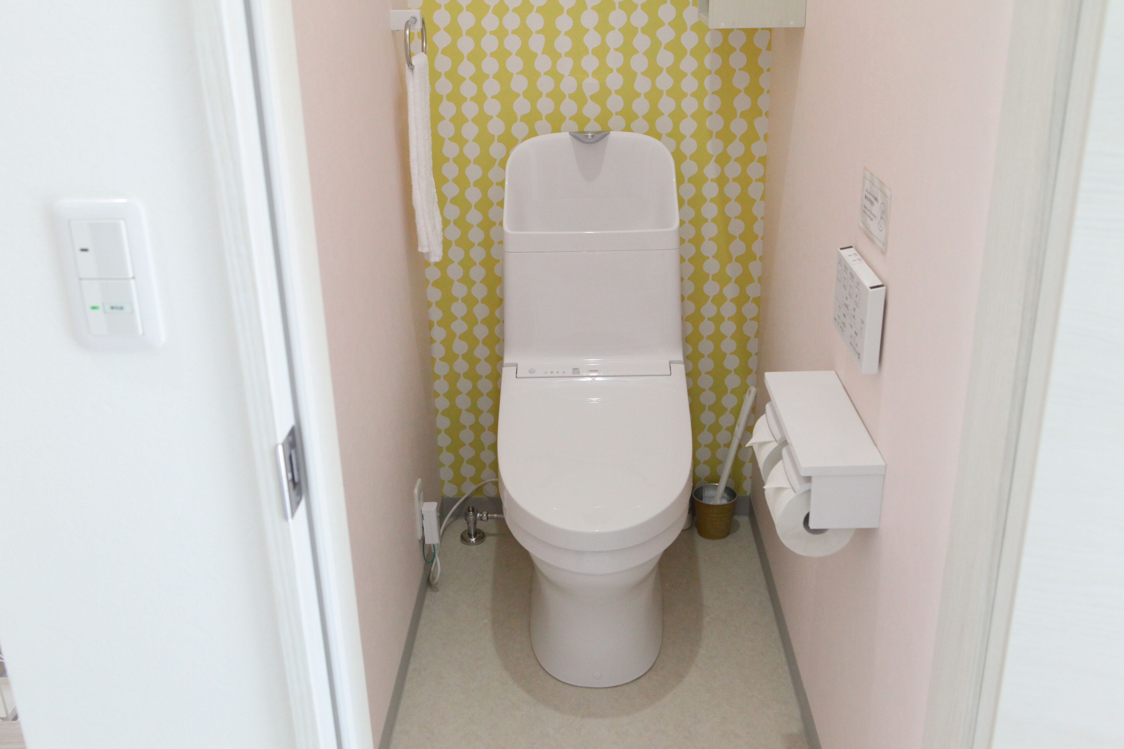 A small, compact bathroom with a toilet, a hand dryer, and a paper towel dispenser.