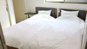 Ein ordentlich bezogenes Bett mit weißen Leinen, ein Zimmer mit einem hölzernen Kopfteil und einem kleinen Nachttisch.