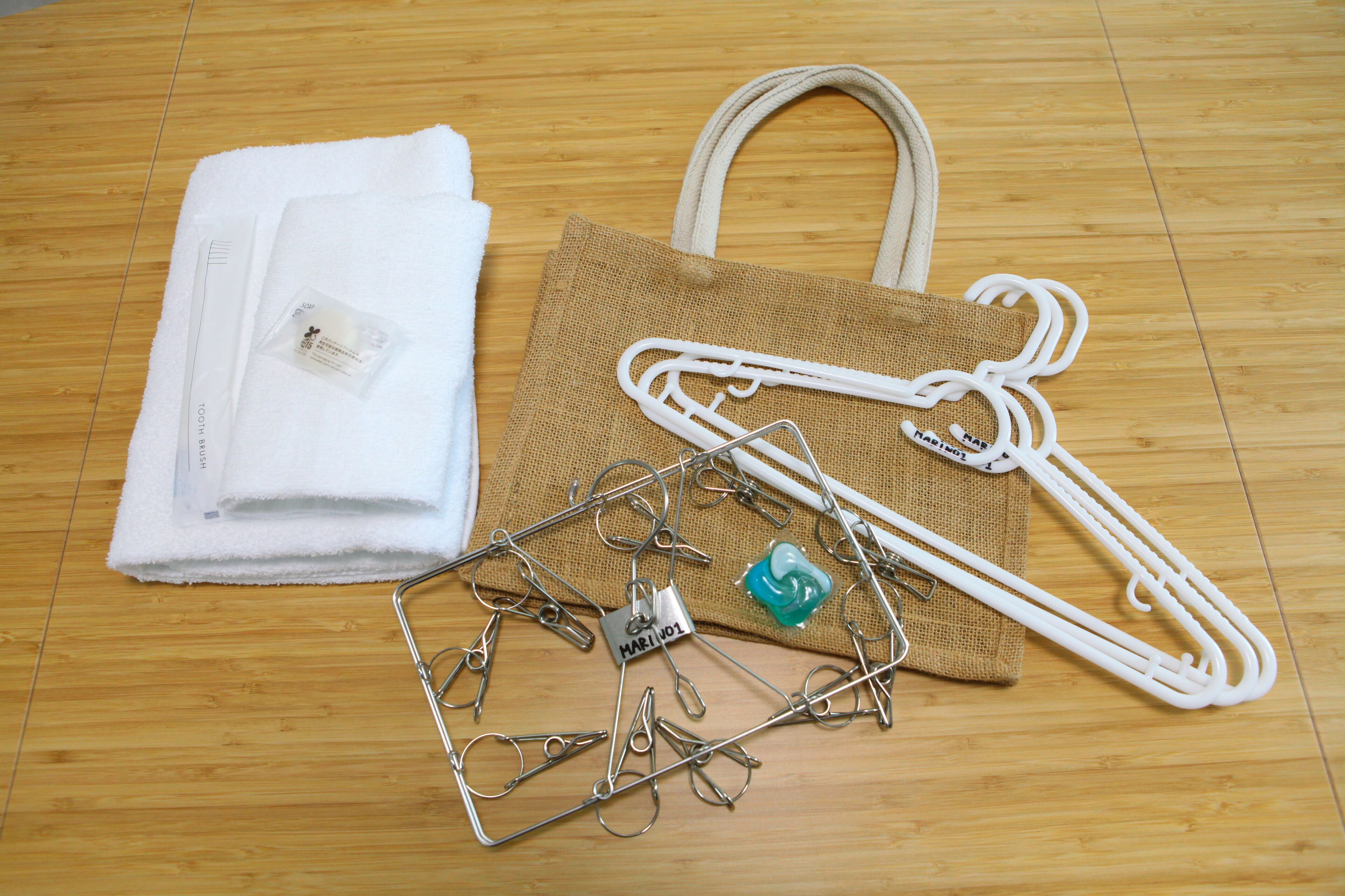 A wooden floor with a white towel, a white plastic bag, and a metal hanger with clips.