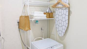 A laundry area with a washing machine, a drying rack, and a towel rack.