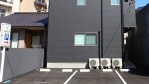 Ein zweistöckiges Gebäude mit dunkelgrauer Fassade, einer flachen Dachkonstruktion und einem Parkplatz davor.