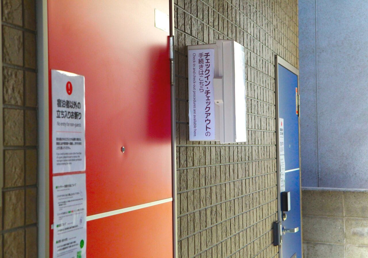 A room with a red door, a blue door, and a sign with Japanese text.