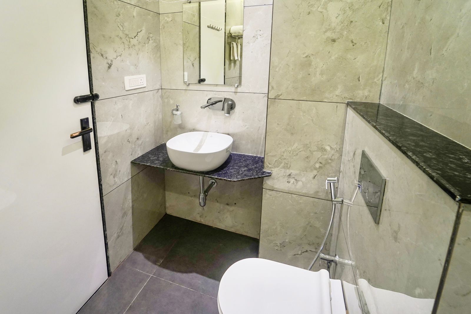 A compact bathroom with a white sink, a mirror, and a shower.