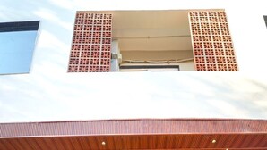 Un edificio moderno con techo inclinado, amplios ventanales y una serie de escalones que conducen a una puerta.