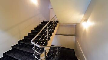 Una escalera moderna con escalones de mármol negro y barandales de metal, que conduce a un rellano con pasamanos.