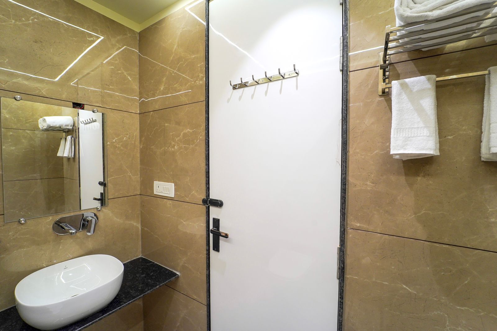 Une salle de bain avec un lavabo blanc, un miroir, un porte-serviettes et une serviette accrochée au mur.