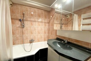 A modern bathroom with a bathtub, a sink, and a shower. - Chic Urban Seaside Apartment (Nieuwpoort)