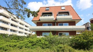 Un immeuble à plusieurs étages, doté d’un toit recouvert de tuiles rouges et de balcons.