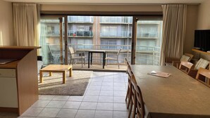 Une chambre d’hôtel moderne dotée d’un balcon, d’un coin repas et d’une télévision.
