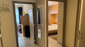 Une chambre d’hôtel comprenant un lit, une salle de bain et un couloir menant à une autre salle de bain équipée d’une douche et d’un porte-serviettes.