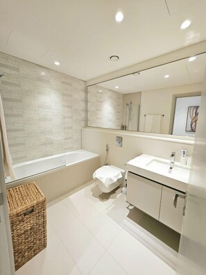 A modern bathroom with a bathtub, toilet, and sink. - 2BRwith Panoramic Sea View in Beachfront (Dubai)