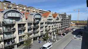 Een hotel met meerdere verdiepingen, balkons, een parkeerplaats en een bouwkraan op de achtergrond.