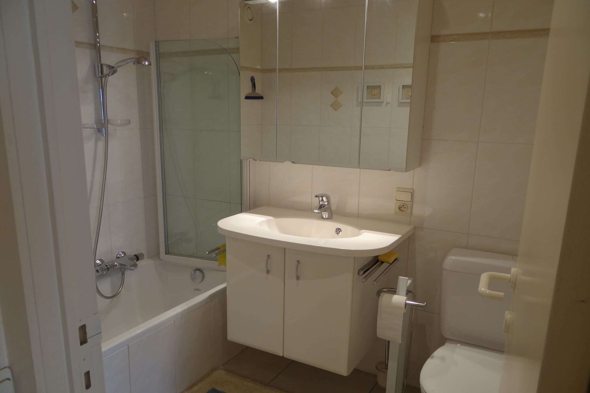 A bathroom with a bathtub, a sink, a toilet, and a glass shower enclosure.