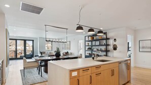 A modern kitchen with wooden cabinets, a central island, and pendant lighting. - Frontgate 302 - 5 Bedroom Residence (Avon)