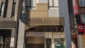 Un hotel con fachada moderna, numerosas ventanas y una entrada destacada.