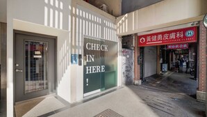 Un escaparate con un cartel que dice 'CHECK IN HERE', una tienda cerrada con un letrero rojo y una tapa de alcantarilla en la acera.