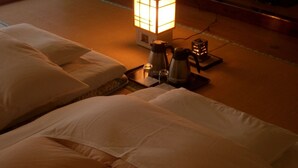 A hotel room with a bed, pillows, a bedside table with a lamp, and a small decorative item.