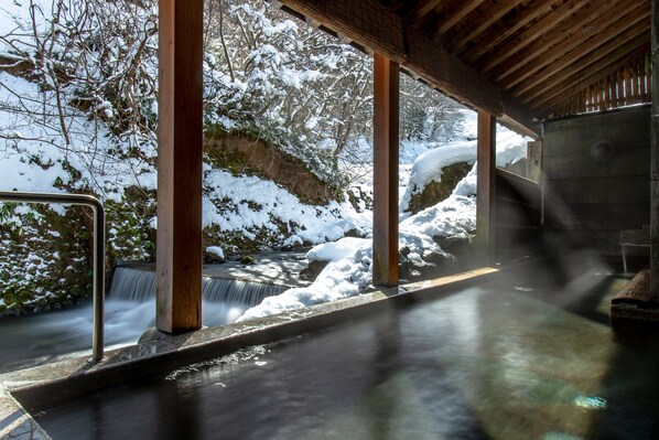 A wooden structure with a view of a waterfall and snow-covered landscape.
