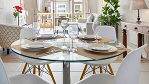 A dining area with a glass table, white chairs, and a view of a balcony. - Bougain Villa CB206 (Cape Town)