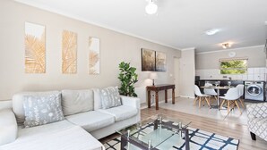 A modern living room with a sofa, coffee table, and artwork on the walls. - Bougain Villa CB206 (Cape Town)