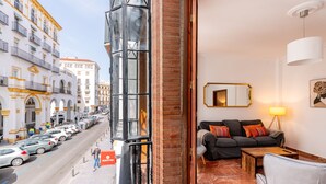 A hotel room with a view of a busy street, a sofa, a table, and a mirror. - Pastor y Landero 17. 2-bedrooms. Arenal area (Sevilla)