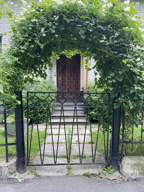 A wooden door with a decorative metal gate in front. - Eklinds Rum och Trädgård (Gothenburg)