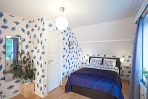 Une chambre à coucher avec un lit, une commode, un miroir et une plante en pot.