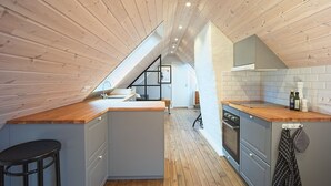 Une cuisine moderne avec des poutres en bois, un îlot central et une vue sur l’espace de vie.