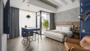Een moderne hotelkamer met een bed, bureau en lederen fauteuil.