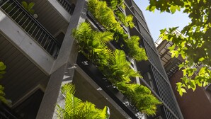Een modern gebouw met meerdere balkons, waarvan sommige beplant zijn.