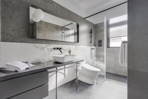 A modern bathroom with a large mirror, a white sink, and a glass-enclosed shower.