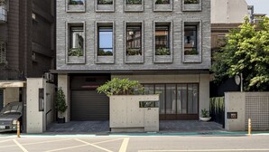 Een modern meerlaags gebouw met een raamrooster en balkons, met een plat dak en een garage-ingang.