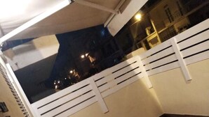 Ein Außenbereich mit gefliestem Boden, weißen Geländern und einem Gebäude im Hintergrund.