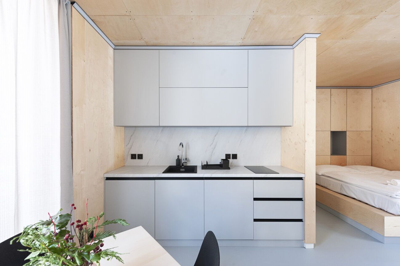 A compact kitchen with a white countertop, a sink, and a small dining area with a table and chair.